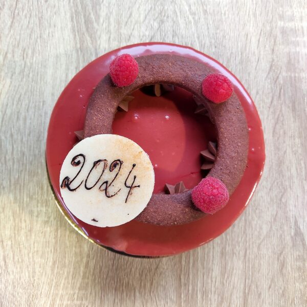 Couronne de l'Avent en mousse de chocolat noir et framboise, avec un insert gélifié framboise et un glaçage au chocolat, un dessert festif et délicieux pour les fêtes.